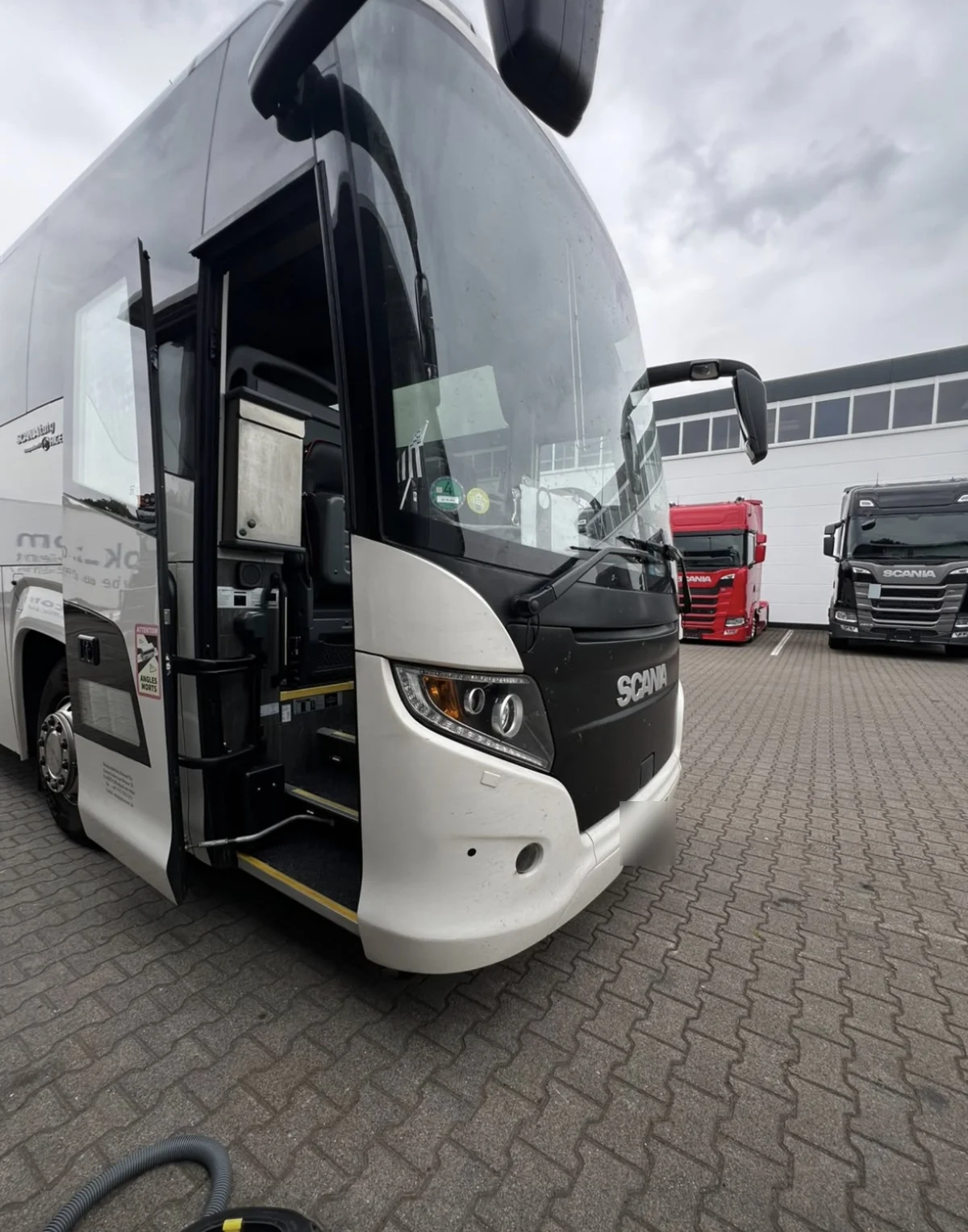 Scania Reisebus mit geöffneter Einstiegstür auf dem Betriebshof