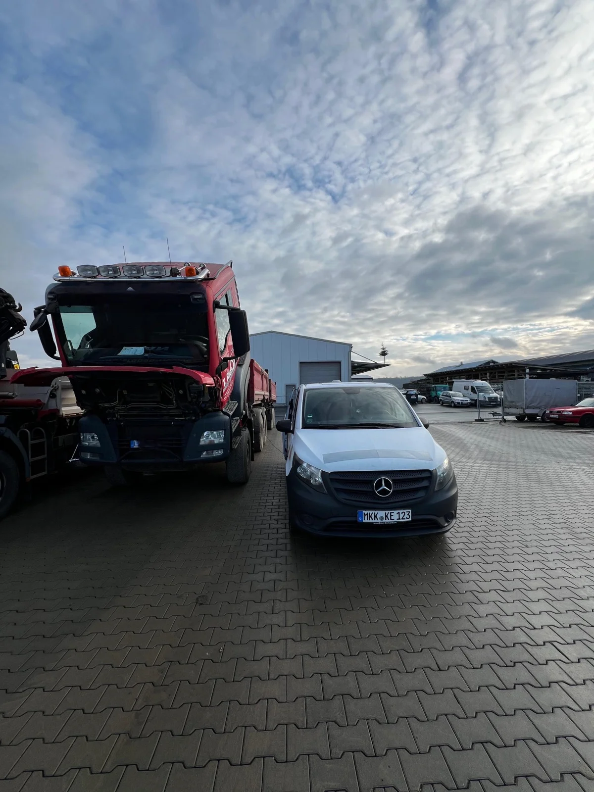 Kipper-LKW mit geöffneter Motorhaube und Servicetransporter auf dem Hof